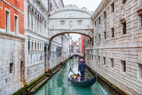 Gondola under historic Venetian bridge.